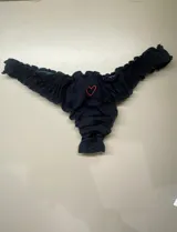 Bombacha tipo less de algodón negro con volados en los bordes y un pequeño corazón bordado en color rojo en la parte frontal.