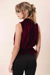 Blusa de terciopelo color borgoña, sin mangas, con escote drapeado y peplum elastizado en la cintura.