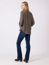 Blusa de gasa estampada con patrón geométrico en tonos azul, marrón y amarillo. Cuello a la base con detalle plisado y escote en V. Manga larga con presilla y botón para regular el largo.