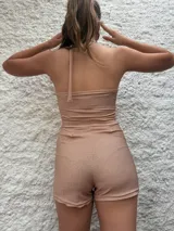 Mono corto dorado de lurex, con escote halter asimétrico y choker integrado.