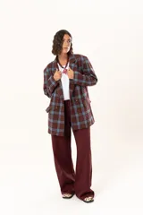 Blazer de corte oversize con estampado de cuadros en tonos azul, bordó y marrón. Presenta solapas clásicas, bolsillos con solapa en el frente y cierre frontal con botones.