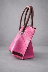 Cartera de cuero con textura crocco en color rojo, de silueta estructurada, manijas largas marrones y detalles de terminación artesanal en el borde superior.