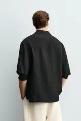Camisa tipo kimono de corte relaxed fit, color celeste, confeccionada en tejido fluido de viscosa y lino. Presenta cuello con solapas de muesca, manga corta y cierre frontal cruzado con doble botonadura.