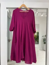 Vestido midi de lino color magenta, con escote en V, mangas tres cuartos y corte amplio y fluido.