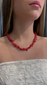 Gargantilla tipo choker compuesta por pequeñas figuras de estrellas de mar en color rojo, intercaladas con cuentas doradas.