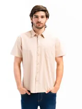 Camisa de manga corta color celeste claro, confeccionada en algodón, con cuello clásico y un bolsillo de parche en el lado izquierdo del pecho.