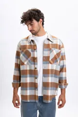 Sobrecamisa de manga larga con diseño a cuadros en tonos tostado, gris y blanco. Presenta cuello clásico, cierre frontal con botones y dos bolsillos delanteros con solapa.