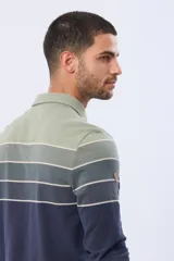Remera polo de manga larga con diseño rayado en degradado de tonos azules y grises, cuello liso azul marino y logo bordado en el pecho. Confeccionada en tejido piqué de algodón.