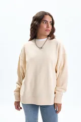 Buzo deportivo color crudo de manga ancha y corte holgado, con cuello redondo y puños y ruedo acanalados.