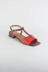 Sandalias de cuero combinadas en negro y marfil, con diseño de tiras en T, taco cuadrado bajo y pulsera con hebilla ajustable al tobillo.