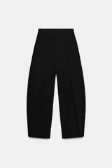 Pantalón negro de tiro alto con detalle de pliegues en el delantero, bolsillos laterales ocultos y cierre frontal con cremallera, botón interior y ganchos metálicos.