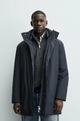 Parka acolchada impermeable color gris oscuro, de corte regular fit, con cuello doble subido, bolsillos de vivo en la cadera y cierre frontal con cremallera oculta por solapa con botones a presión.