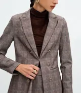 Blazer femenino de corte acinturado confeccionado en tejido punto roma con estampado de cuadros. Presenta solapas estructuradas, cierre frontal de doble botonadura, mangas con botones decorativos y recortes traseros.