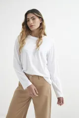 Remera blanca de algodón, de manga larga y cuello redondo. Corte recto y holgado.