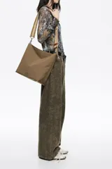 Bolso bandolera de tamaño pequeño confeccionado en nylon, con estructura blanda y cierre de cremallera. Cuenta con asa larga regulable de tejido y logo de la marca aplicado en la parte inferior frontal.