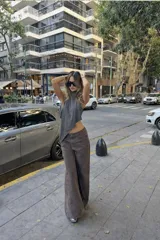 Top de satén color marrón con escote halter y diseño asimétrico en punta. Posee espalda descubierta y cierre con lazo fino en el cuello.