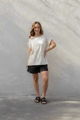 Blusa de corte holgado y manga corta con dobladillo, confeccionada en una mezcla de algodón y lino. Presenta un cuello redondo amplio y un diseño minimalista en color beige.