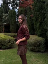 Blazer de jean azul con cuello, solapa y cuatro botones frontales. Presenta volados de encaje negro en cuello y delantero, mangas largas con pliegues y bolsillos plaqué. Interior con terminación en hilo bordó.