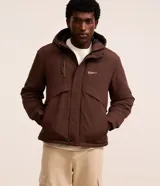 Campera marrón para hombre confeccionada en poliamida, con capucha ajustable con cordón, cierre frontal con cremallera, bolsillos laterales invisibles, bolsillo en el pecho con cremallera, recortes y estampado de letras en el pecho.