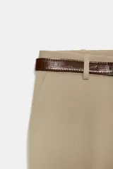 Pantalón de tiro alto color negro, de corte recto y pinzas frontales. Incluye un cinturón delgado de cuero marrón con hebilla metálica dorada.