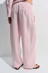 Pantalón de tiro medio confeccionado en 100% lino color rosado, con diseño de pernera ancha, pinzas en el delantero, cintura elástica en la parte posterior y bolsillos laterales. Cuenta con cierre frontal con cremallera y botón.