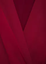 Vestido corto rojo con escote en V cruzado, sin mangas y con detalle drapeado en la falda.