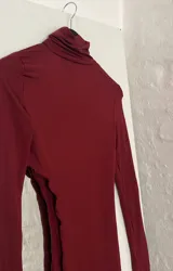 Top de cuello alto color bordó, con manga larga y abertura en el abdomen.
