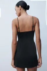 Vestido corto satinado negro con escote corazón, tirantes finos y cierre frontal con corchetes metálicos.