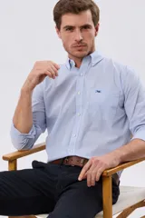 Camisa de manga larga con estampa de cuadros pequeños en tonos celeste y blanco, cuello con botones y bolsillo ojal en el pecho con detalle bordado.