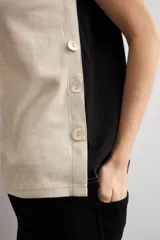 Remera sin mangas de corte recto, confeccionada en dos tonos, con frente en color beige claro con escote en V y espalda en color negro. Cuenta con detalle de botones en los laterales.