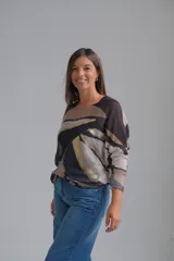 Sweter de punto con diseño abstracto en tonos tierra, negro y detalles metalizados dorados. Presenta cuello redondo, mangas largas con puños ajustados y un corte holgado.