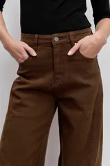 Pantalón de jean color marrón, de corte recto y tiro medio, con cierre de botón y cremallera, y bolsillos laterales.