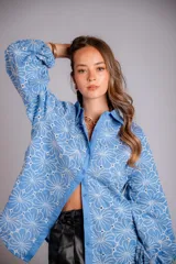 Camisa de manga larga con diseño abullonado, confeccionada en tela bordada con motivos florales. Presenta cierre frontal con botones y puños elásticos.