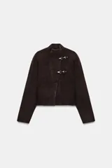 Chaqueta corta de punto marrón con cuello subido, manga larga y cierre frontal cruzado con alamares metálicos plateados.