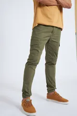 Pantalón cargo color beige con ajuste slim, cierre frontal con botón, bolsillos laterales tipo cargo y puños elásticos en los tobillos.
