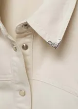 Camisa de estilo vaquero confeccionada en algodón, con cuello camisero, cierre frontal con botones metálicos y mangas largas con puños abotonados. Presenta un diseño entallado con costuras frontales.