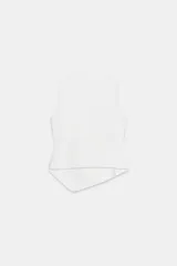 Top de punto blanco sin mangas, de cuello redondo y corte ajustado. Presenta un diseño asimétrico con una solapa cruzada decorada con una hilera de botones metálicos oscuros dispuestos en diagonal que se extienden hasta el dobladillo asimétrico.