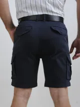 Bermuda color beige, estilo cargo, con bolsillos laterales con solapa y cierre de botón. Incluye cinturón de cuero marrón.