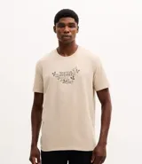 Remera de algodón color beige con cuello redondo, mangas cortas y estampa frontal con lettering y motivos botánicos.