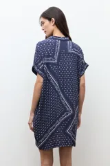 Vestido túnica azul marino con estampado paisley y floral blanco, de corte recto, manga corta y cierre frontal con botones.