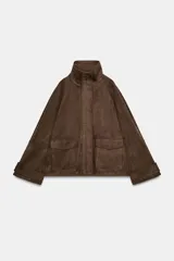 Chaqueta de tejido efecto ante color marrón, con cuello alto, cierre frontal con cremallera y botones a presión, manga larga y bolsillos de plastrón con solapa en el delantero.