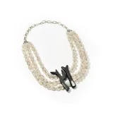 Collar de tres hilos de mostacillas transparentes con cadena plateada y dije negro con forma abstracta.