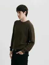 Sweater de punto con textura en color verde oscuro, de cuello redondo y manga larga.