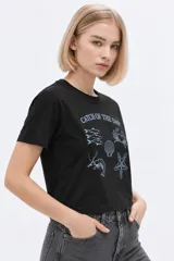 Remera de manga corta de algodón, color blanco, con cuello redondo y estampado frontal estilo collage con gráficos y texto en tono bordó.