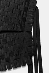 Top asimétrico de diseño trenzado color negro, con un solo tirante y lazadas laterales.