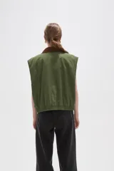 Chaleco de algodón color verde oliva, con cierre frontal y cuello de pana en color marrón. Presenta un diseño holgado con elástico en la cintura.
