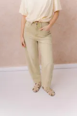 Jean de calce relajado y pierna amplia color beige, con tiro alto y detalle de recortes y costuras visibles.