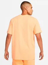 Remera Nike Sportswear Club de color salmón, de corte clásico y mangas cortas, con el logotipo de Futura bordado en blanco en el pecho.