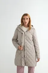Campera acolchada de largo medio con diseño de rombos, cierre frontal con cremallera y solapa con botones a presión. Incluye capucha desmontable y bolsillos laterales.
