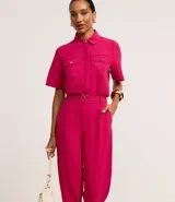 Pantalón zanahoria color fucsia de tiro alto, confeccionado en tejido airflow, con cintura elastizada, trabillas y hebillas metálicas.